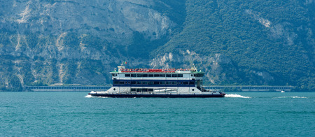 Ferry boat with tourists during navigation on Lake Garda near Malcesine, Veneto, Italy. In the background the coast of Lombardyの写真素材