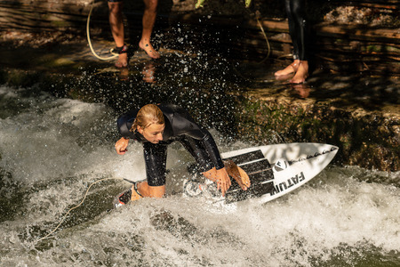 MUNICH, GERMANY - SEPT 8, 2018: Man surfing in the waves of the Eisbach River in Munich. It forms a...