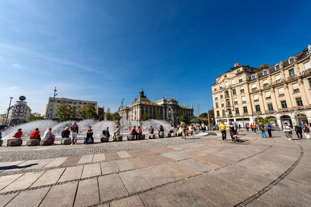 MUNICH, GERMANY - SEPT 6, 2018: Tourists and locals visit the Karlsplatz or Stachus, large square in central Munich with a fountain, in background the Palace of Justice (Justizpalast).のeditorial素材