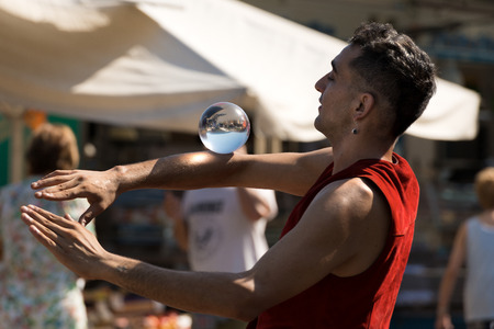 LERICI, LIGURIA, ITALY, JULY 19, 2014: Unidentified young juggler with a crystal ball, shows his art to the public in the Lerici Village, Liguria, italyのeditorial素材