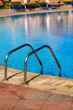 Close-up of a swimming pool with a ladder in stainless steel and blue waterの写真素材