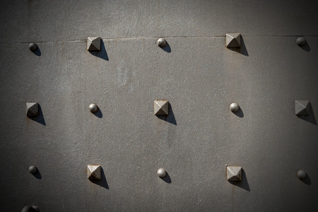 Detail of an old metal door with studs in the shape of a pyramid
