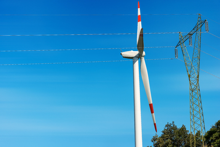 Wind turbine and high voltage tower (power line) on a clear blue sky - Renewable energy concept