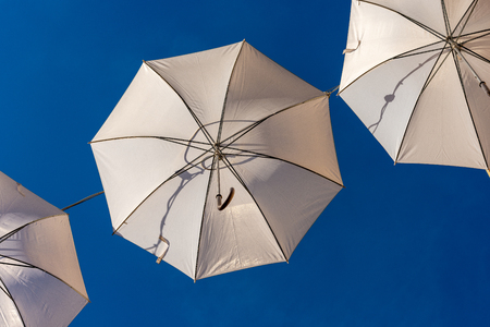 Group of three white umbrellas on a clear blue sky, used as city lightingの写真素材