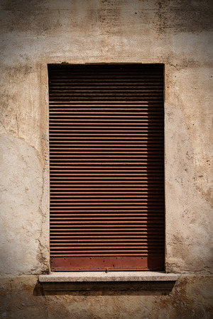 Close-up of an old rusty closed roller shutter of a shop. Concept of economic crisisの写真素材