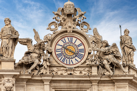 Basilica of Saint Peter. Close-up of one of the two clocks with marble statues and the Coat of arms of the Vatican city.の写真素材
