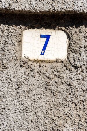 Old house number seven on the wall in a small village. Liguria, Italy, Europe
