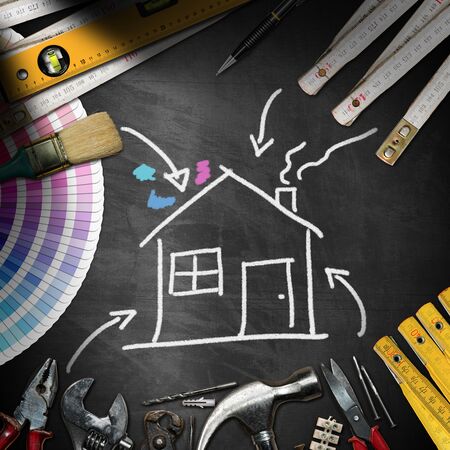Home improvement concept - Black chalkboard with work tools and a chalk drawing of a houseの写真素材