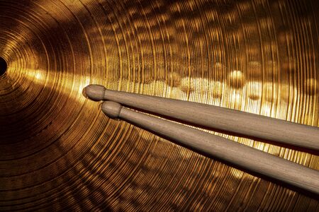 Close-up of two wooden drumsticks on a golden colored cymbal. Percussion instrumentの写真素材