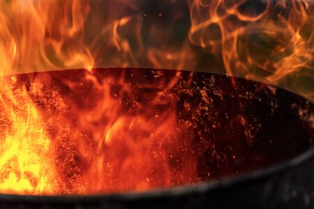 Close-up of red, yellow and orange flames in a blackened old metal binの写真素材