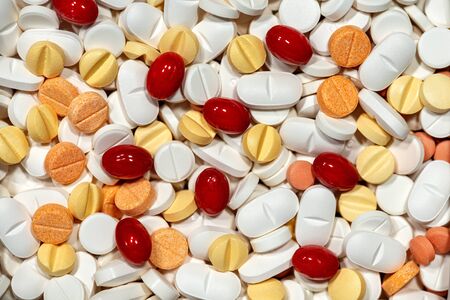 Close-up of a large group of white, red and yellow medicine pills. Photography full frame