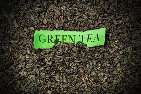 Close-up of many dried leaves of green gunpowder tea and piece of paper with text Green Teaの写真素材