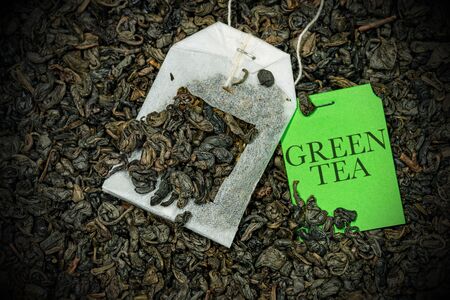 Close-up of a green tea bag, Gunpowder tea, with label on a many dried leaves for preparing a hot drinkの写真素材