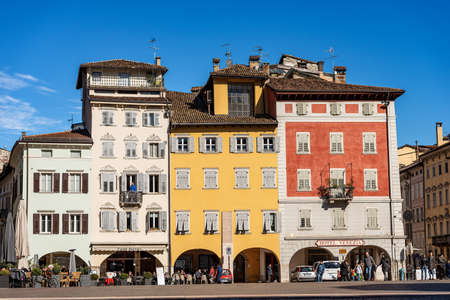 TRENTO, TRENTINO ALTO ADIGE, ITALY - MARCH 8th, 2020: Piazza del Duomo, Cathedral square in Trento city with the typical houses. People stroll in the square or sit in the bars on a sunny winter dayのeditorial素材