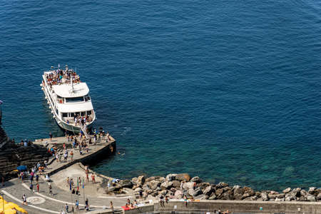 VERNAZZA, LIGURIA, ITALY - JULY 22, 2019: Aerial view of the port of the ancient Vernazza village with a ferry boat with many tourists. Cinque Terre, National park, Liguria, La Spezia, Italy, Europeのeditorial素材
