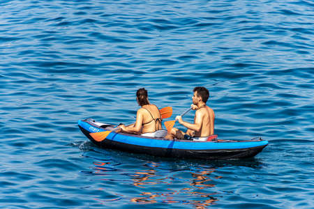 GULF OF LA SPEZIA, LIGURIA, ITALY - JULY 21, 2019: young couple, a man and a woman paddle in the blue sea on an inflatable kayak. Gulf of La Spezia, Liguria, Italy, Europeのeditorial素材