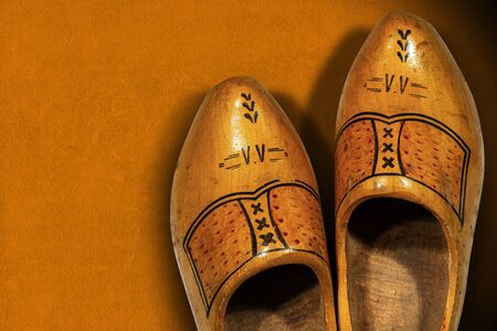 Close-up of a pair of wooden clogs made in Netherlands, on an orange background with copy space, top...
