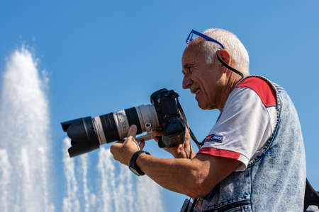 Male photographer with professional equipment (Canon EOS Mark III) while he is performing a photo shoot in downtown of Milan in front of the Sforza Castleのeditorial素材