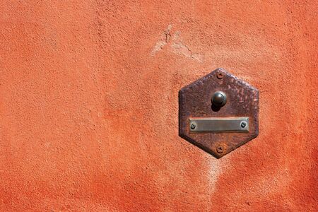 Close-up of an old doorbell with empty nameplate on a red wall with copy space. Tellaro village,...
