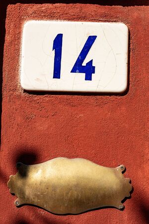 Old house number fourteen and an empty brass plaque with copy space on the red wall, Liguria, Italy, Europeの写真素材