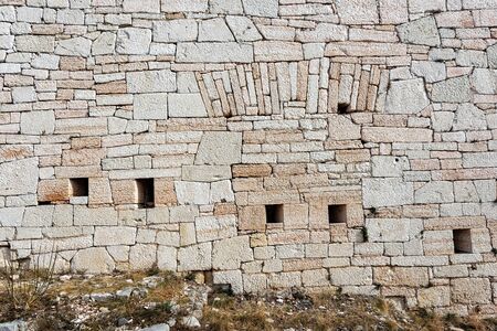Closeup of an Austrian fortified wall made of irregular stone blocks with arrowslits or loopholesの写真素材