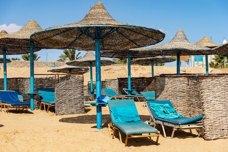 Group of straw umbrellas and deck chairs in a Red Sea sandy beach, tourist resort near Marsa Alam, Egypt, Africaの写真素材