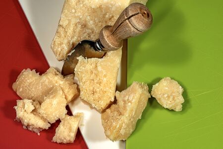 Close-up of Parmesan cheese on a cutting board with the colors of the Italian flag and a knifeの写真素材