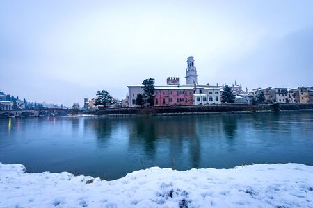 River Adige and Verona cityscape with the Ponte Pietra (Stone bridge, 1st century B.C.) and the bell tower of the Cathedral in winter with snow. Veneto, Italy, Europeの写真素材