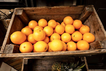 Closeup of an old wooden crate with ripe oranges at market, Tuscany, Italy, Europe
