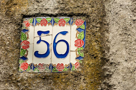 Close-up of house number 56 (fifty six) on the wall in a small village. Liguria, Italy, Europeの写真素材