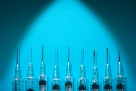 Closeup of a group of syringes on blue background with copy space