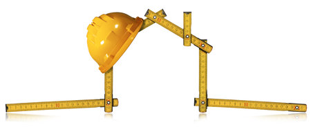 Yellow work helmet over a wooden folding ruler in the shape of house, isolated on white background...