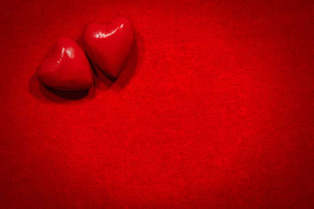 Close-up of two wooden red hearts on a red velvet background with copy space.の写真素材