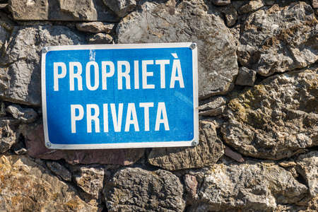Proprieta Privata, Blue and white Private Property sign in Italian language hanging on a stone wall. Liguria, Italy, Europeの写真素材