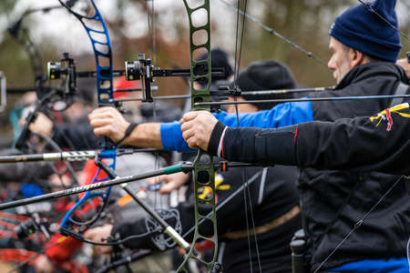 Close-up of a group of archers aiming with hunting compound bows on a cold winter day outdoors. Archery sport concept.のeditorial素材