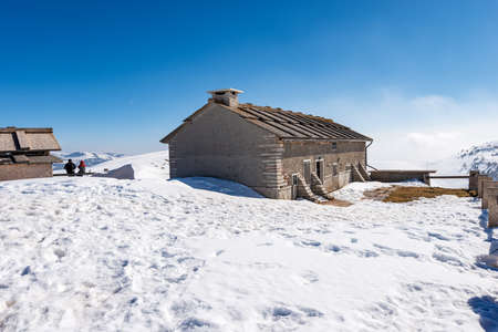 Typical old stone farmhouse and cow shed on Lessinia Plateau (Altopiano della Lessinia) in winter with snow near the peak of Corno d'Aquilio. Sant'Anna d'Alfaedo municipality, Veneto, Italy, Europe.の写真素材