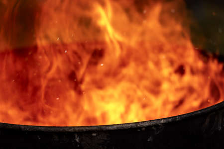 Close-up of red, yellow and orange flames in a blackened old metal bin