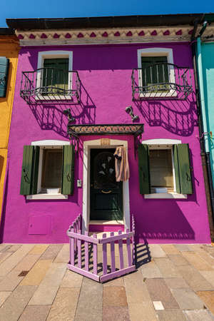 Old small beautiful house with bright colors (magenta and green) in Burano island in a sunny spring day. Venetian lagoon, Venice, UNESCO world heritage site, Veneto, Italy, southern Europe.のeditorial素材