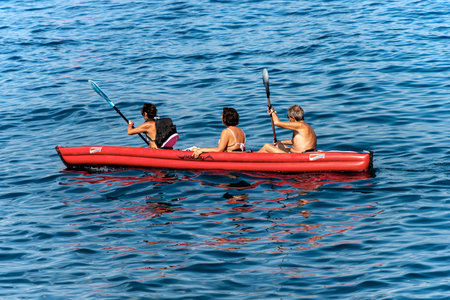 Three senior adults aboard an red inflatable kayak, paddling in the blue Mediterranean sea, Gulf of La Spezia, Liguria, Italy, Europeのeditorial素材