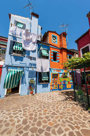 Burano island, houses with bright colors and clothes hanging on clotheslines to dry in the sun. House of Bepi, Venetian lagoon, Venice, Italy, Europe.の写真素材