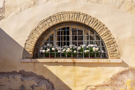 Close-up of an old window with brick arch and wrought iron security bars, Lazise village, Lake Garda, Veneto, Italy, Europe.の写真素材