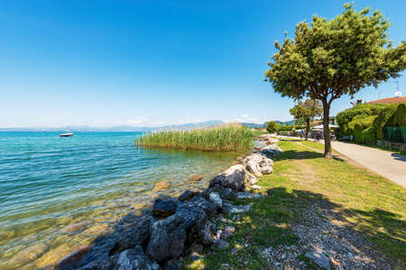 Coast of Lake Garda (Lago di Garda) with the pedestrian and bicycle lane that connects the towns of Lazise, Cisano, Bardolino and Garda. Tourist resorts in Verona province, Veneto, Italy, Europe.の写真素材