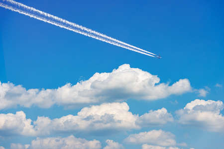 Beautiful storm clouds, cumulus clouds or cumulonimbus against a clear blue sky with an airliner with contrails. Photography, Full frame.の写真素材