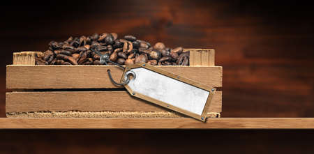 Close-up of roasted coffee beans in a small wooden crate with blank label and copy space, on a wooden table or shelf.の写真素材