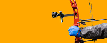 Close-up of the hand with blue glove of an archer aiming with his red hunting compound bow, isolated...