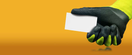 Manual worker with green and black protective work gloves holding a blank business card with copy...