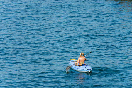 Mature woman aboard a blue kayak, paddling in the blue Mediterranean sea, Gulf of La Spezia, Liguria, Italy, Europe.のeditorial素材