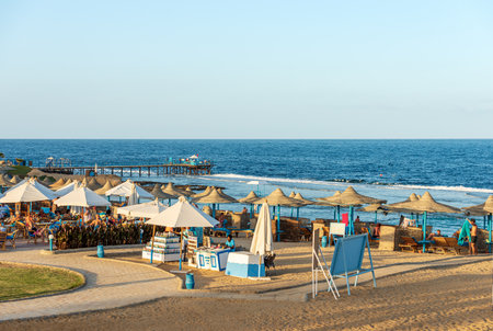 Red Sea near Marsa Alam, sandy beach with straw umbrellas, deck chairs and many tourists, pier above the reef used for diving, snorkeling and swimming. Egypt, Africa.のeditorial素材