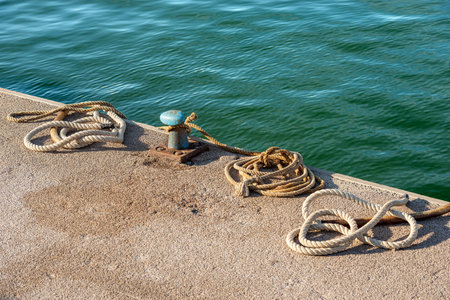 Close-up of a rusty mooring bollard with ropes or hawsers on the quay of the port. Gulf of La...