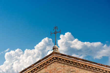 Close-up of a wrought iron religious cross against a clear blue sky with clouds and copy space. Treviso Cathedral (Duomo or Cathedral of San Pietro Apostolo), VI-XIX century, Veneto, Italy, Europe.の写真素材